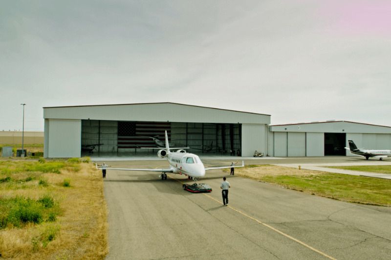 http://zadra-aviationcharter.ch/wp-content/uploads/2017/07/Private-jet-being-guided-by-ground-crew-outside-an-FBO-hangar-highlighting-fixed-base-operator-services-for-private-aviation-travel.png