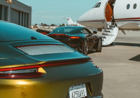 Private jet charter with luxury sports cars parked beside the aircraft on the apron