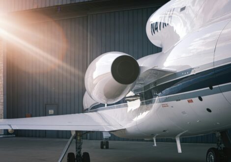 Private jet range aircraft parked near a hangar with sun rays in the background