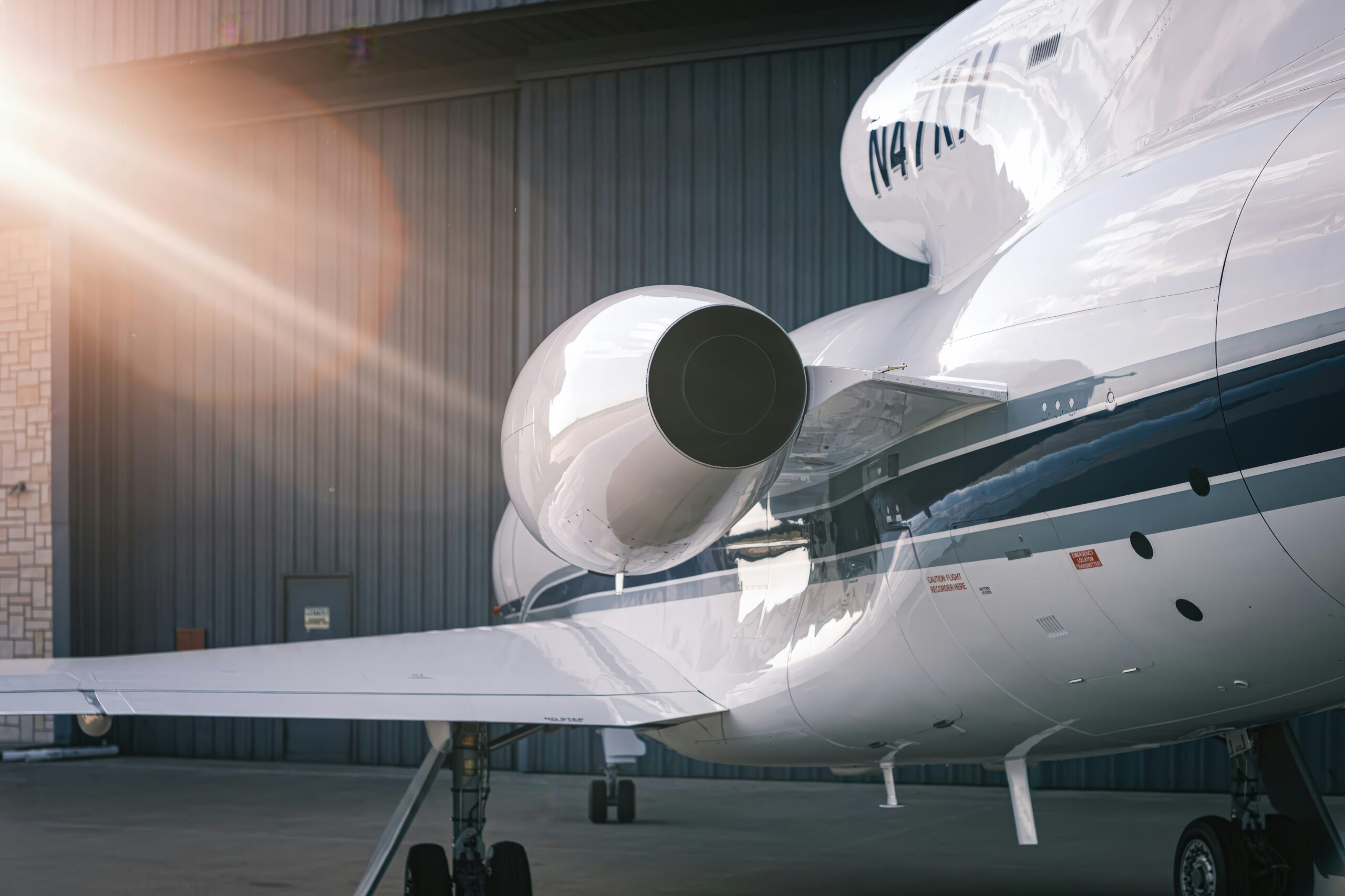 Private jet range aircraft parked near a hangar with sun rays in the background