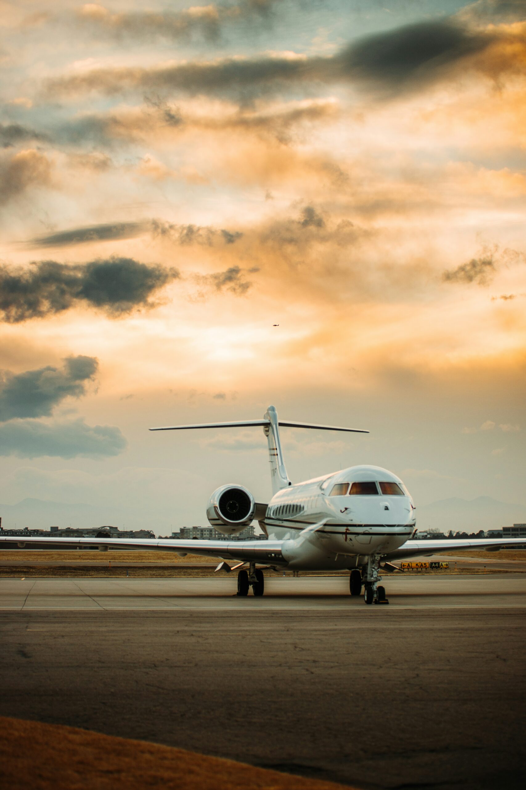 Business jet parked on the airport runway during a sunset